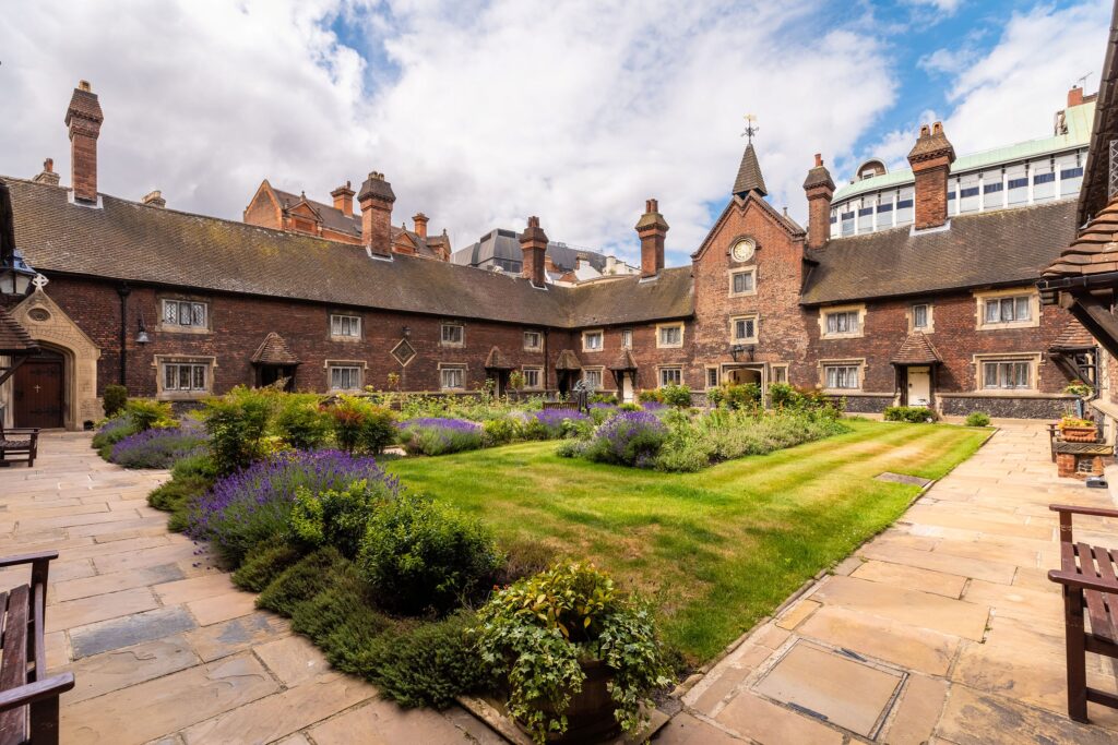 The central courtyard of the Whitgift Almshouses comprising grassed areas and flowerbeds surrounded by a paved walkway