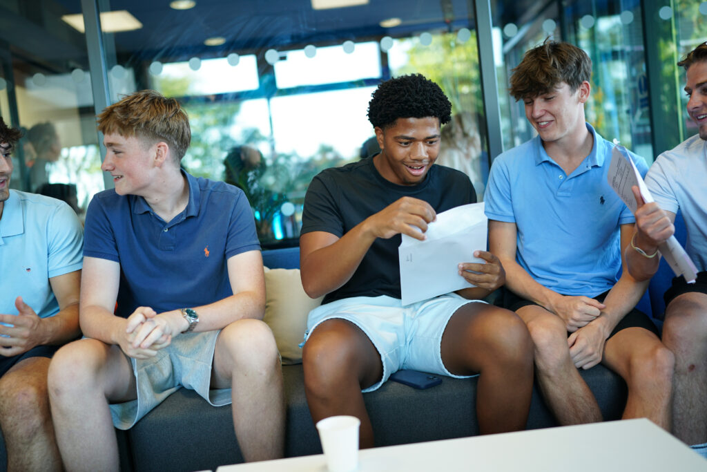 Male students sit together as they read their results